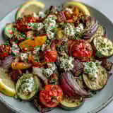 Sizzling roasted Mediterranean Greek vegetables with caramelized edges and bright cherry tomatoes, perfect for a vegetarian dinner.