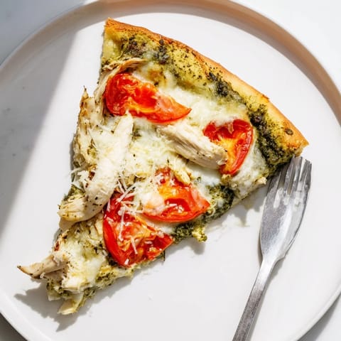 A close-up of Chicken Pesto Pizza featuring tender chicken, basil pesto, and bubbling cheese, ready to serve.  