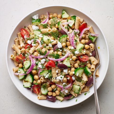 Bright green chickpea pasta salad, loaded with diced cucumber, halved cherry tomatoes, and fresh herbs tossed in a zesty lemon dressing.  