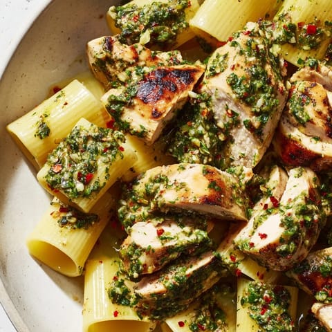 Close-up of Chimichurri Chicken Pasta with herby oil drizzle and a sprinkle of fresh parsley.  