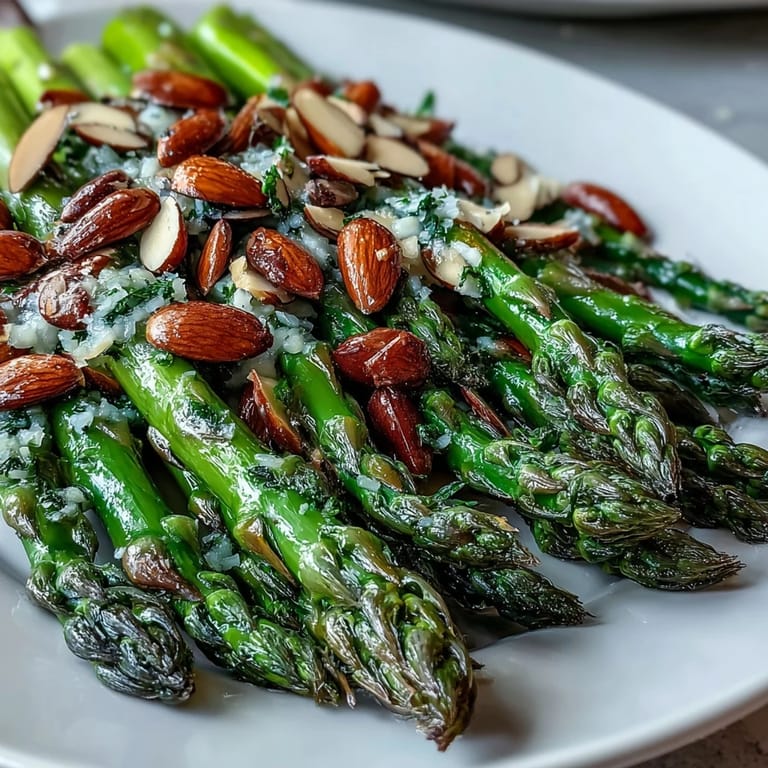 Bright green asparagus sautéed in lemon butter, garnished with toasted almonds for a fresh, elegant side.