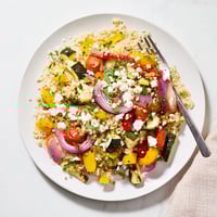 A colorful bowl of Roasted Veggie Couscous Salad with caramelized zucchini, peppers, and tomatoes tossed in bright lemon dressing.  