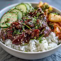 Vibrant Korean beef bowl with spicy gochujang-seasoned ground beef over fluffy rice and colorful pickled vegetables.  